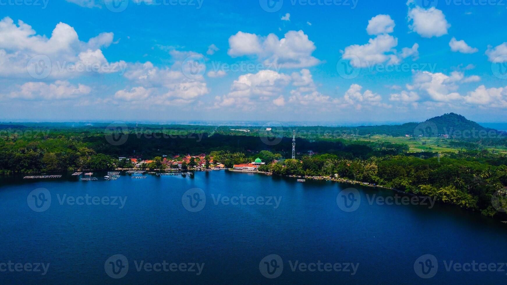 Ranu Bedali Lake in East Java sparkles under a clear blue sky, with Mount Semeru majestically rising in the background. The stunning clouds add to the serene beauty of this breathtaking landscape. photo