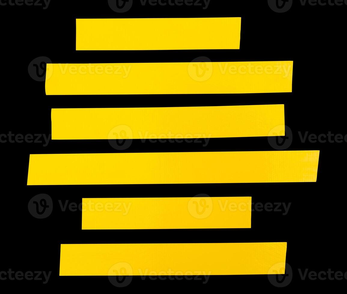 Top view set of yellow adhesive vinyl tape or cloth tape in stripes shape in straight lines isolated on black background with clipping path photo