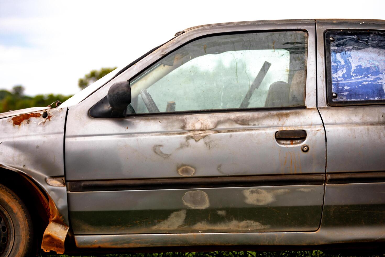Old, weather-damaged, rusty abandoned car photo