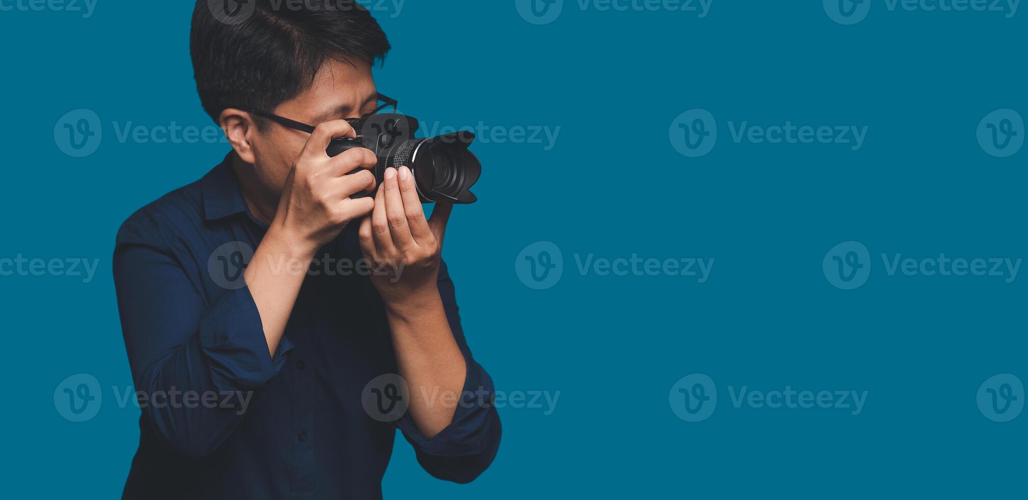 Photographer with a camera. Tomboy's holding the digital camera while standing on a blue background photo