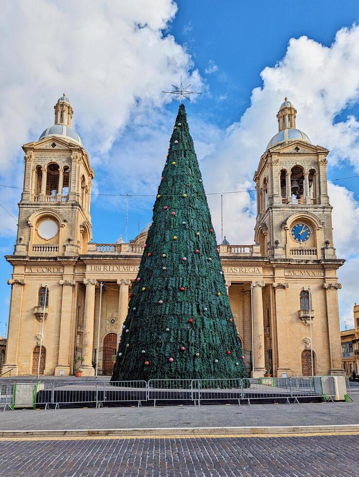 Paola, Malta,16.12.2024 - Christmas Tree in Front of Twin Bell Towers of Historic Christ the King Church in Malta photo