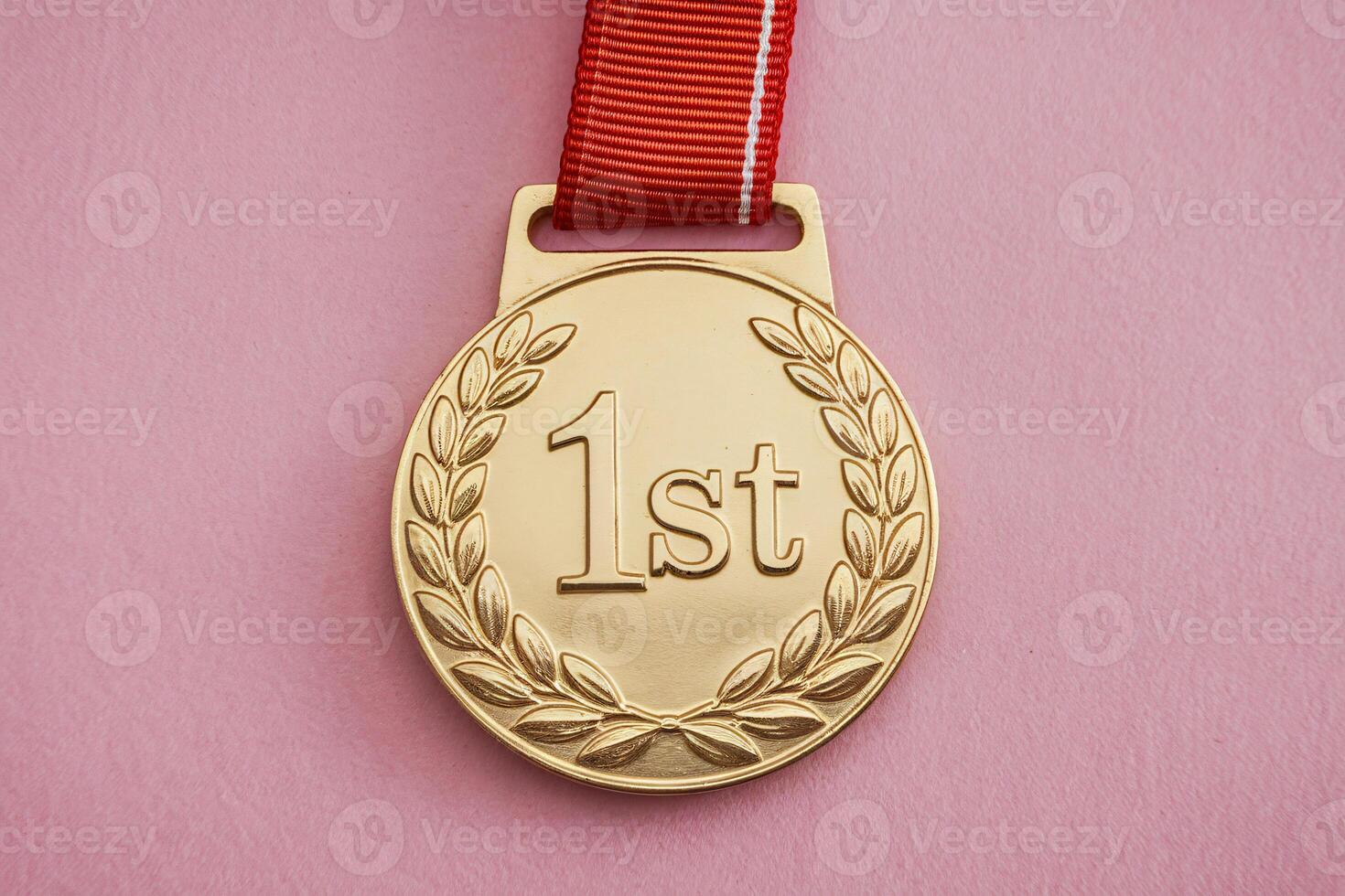 A shiny gold medal with '1st' engraved, symbolizing achievement on a pink background. photo