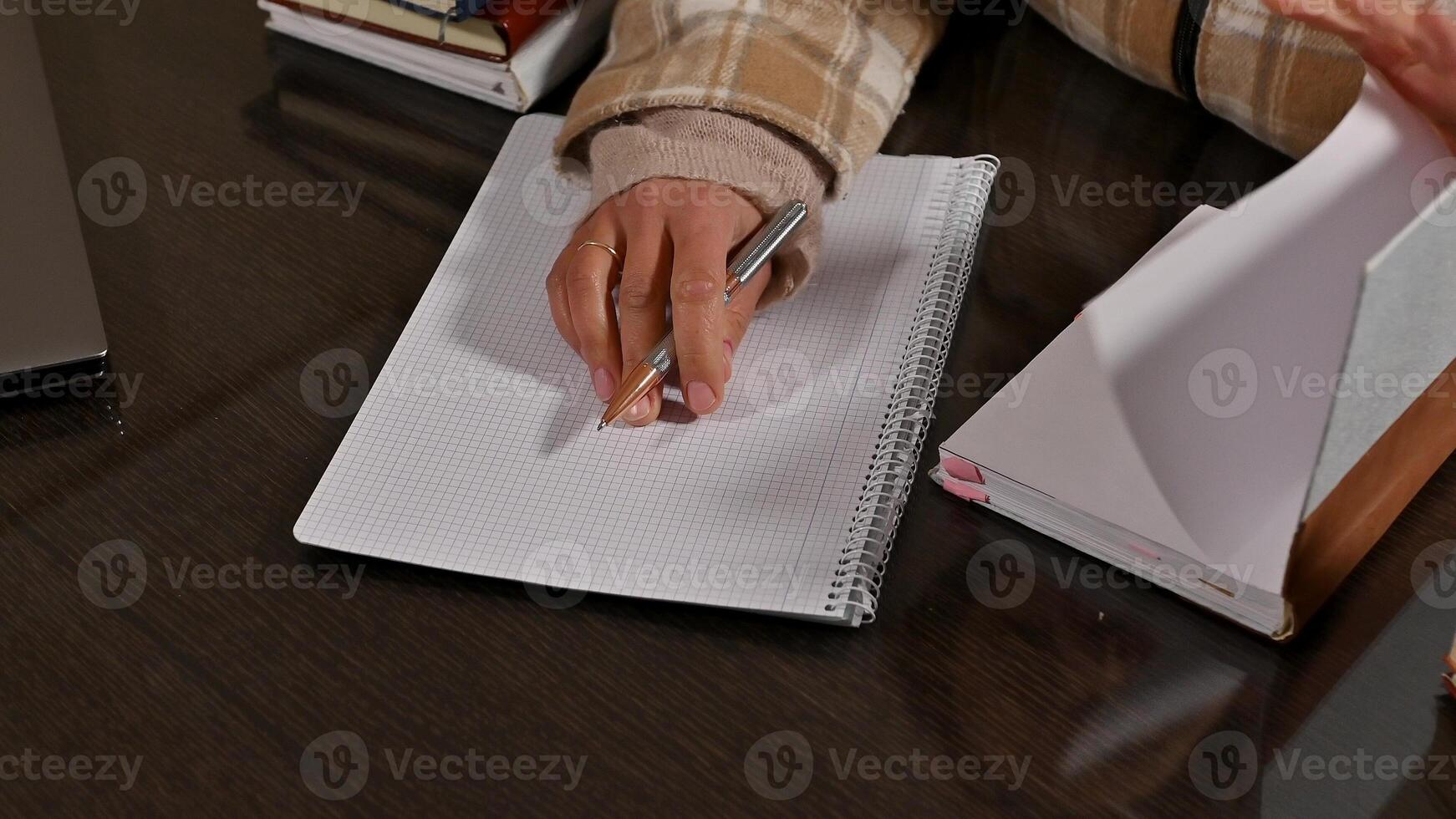 Close-up of a person writing in a notebook with a pen photo
