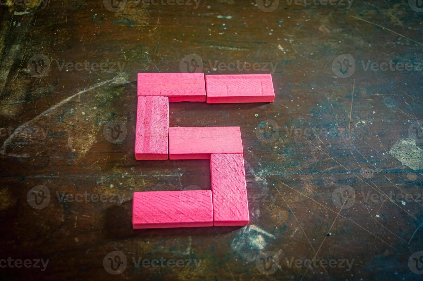 Red wooden blocks arranged in the shape of the number five on a rustic wooden surface. Perfect for educational, numerical, or creative concepts photo