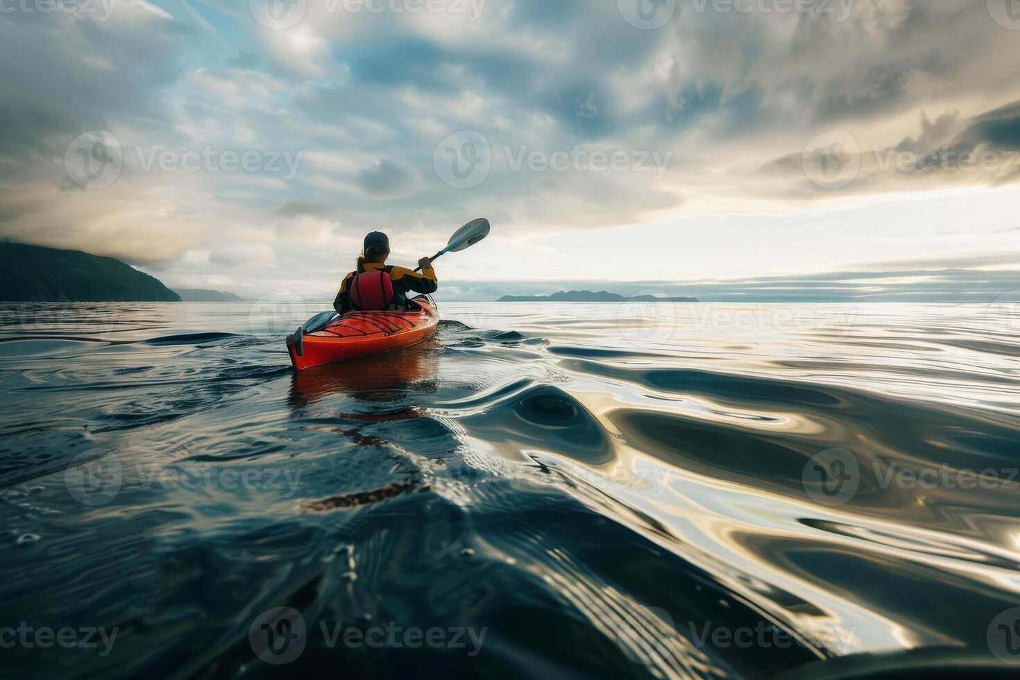 A person kayaking on the ocean with a cloudy sky photo