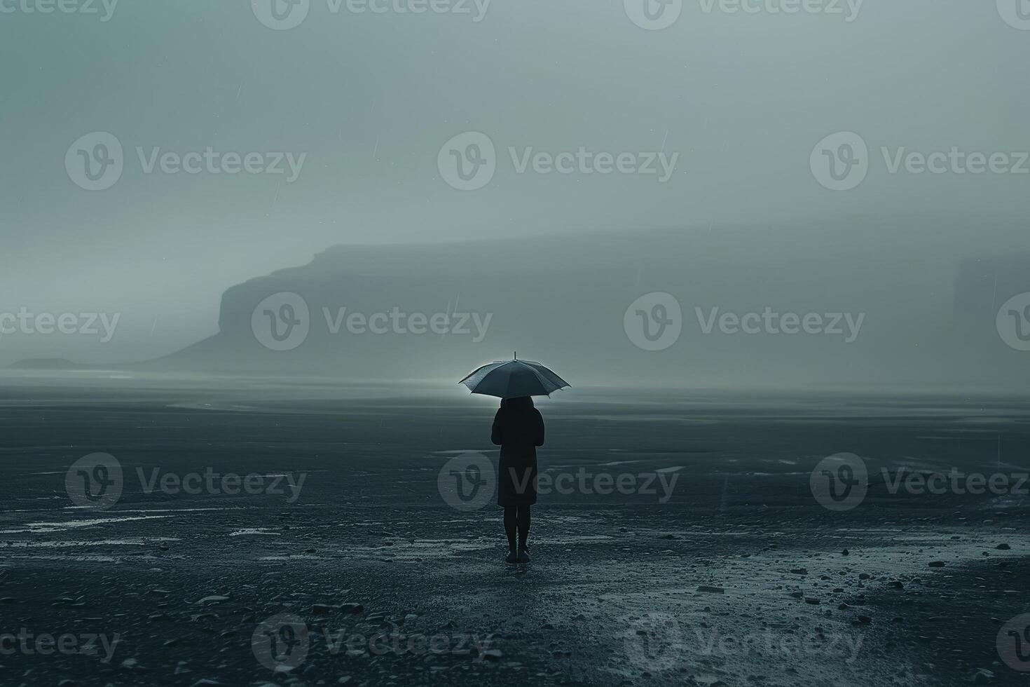 A person standing in the rain with an umbrella photo