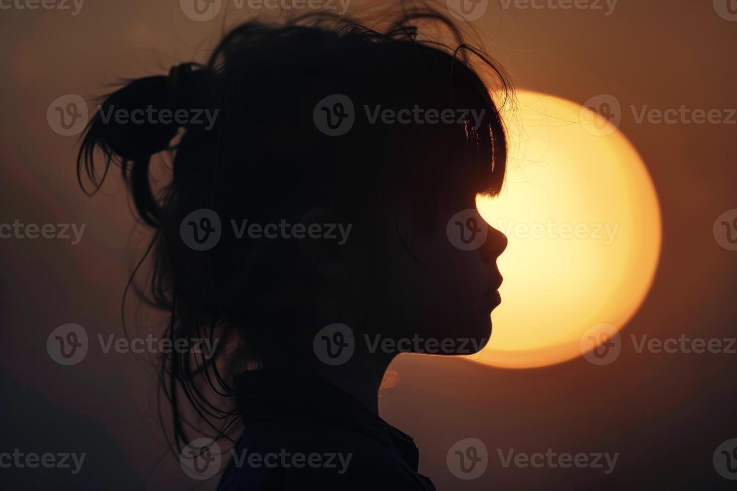 Silhouette of a girl in front of the sun photo