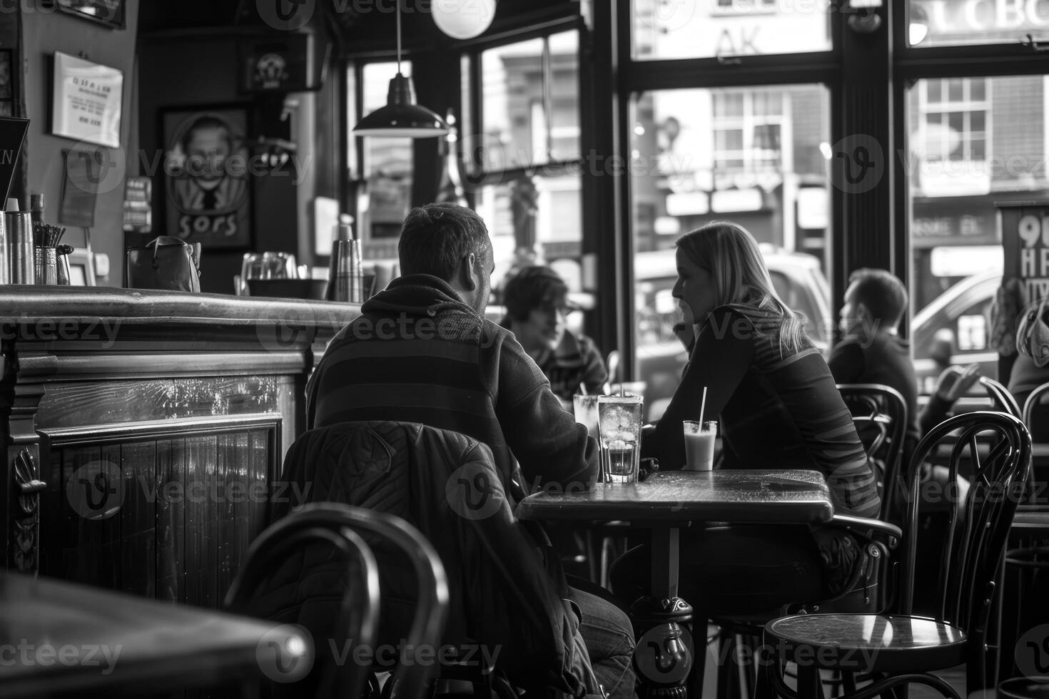 A black and white photo of people sitting at tables in a bar