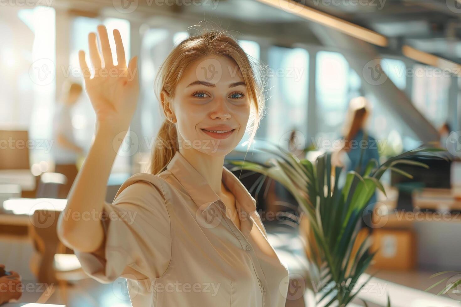 A woman is waving at the camera in a room with a potted plant photo