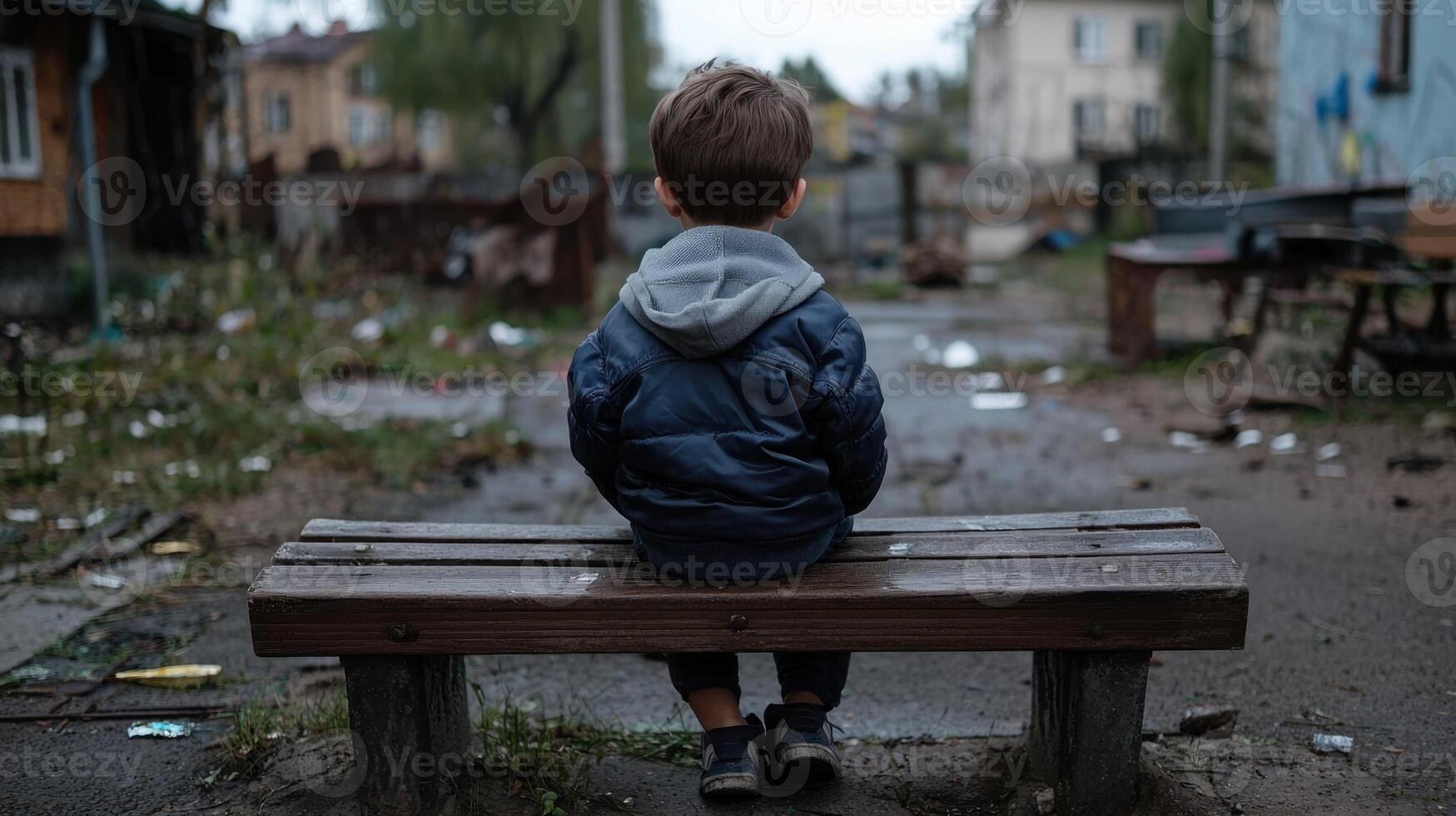 A young boy sitting on a bench in a city photo