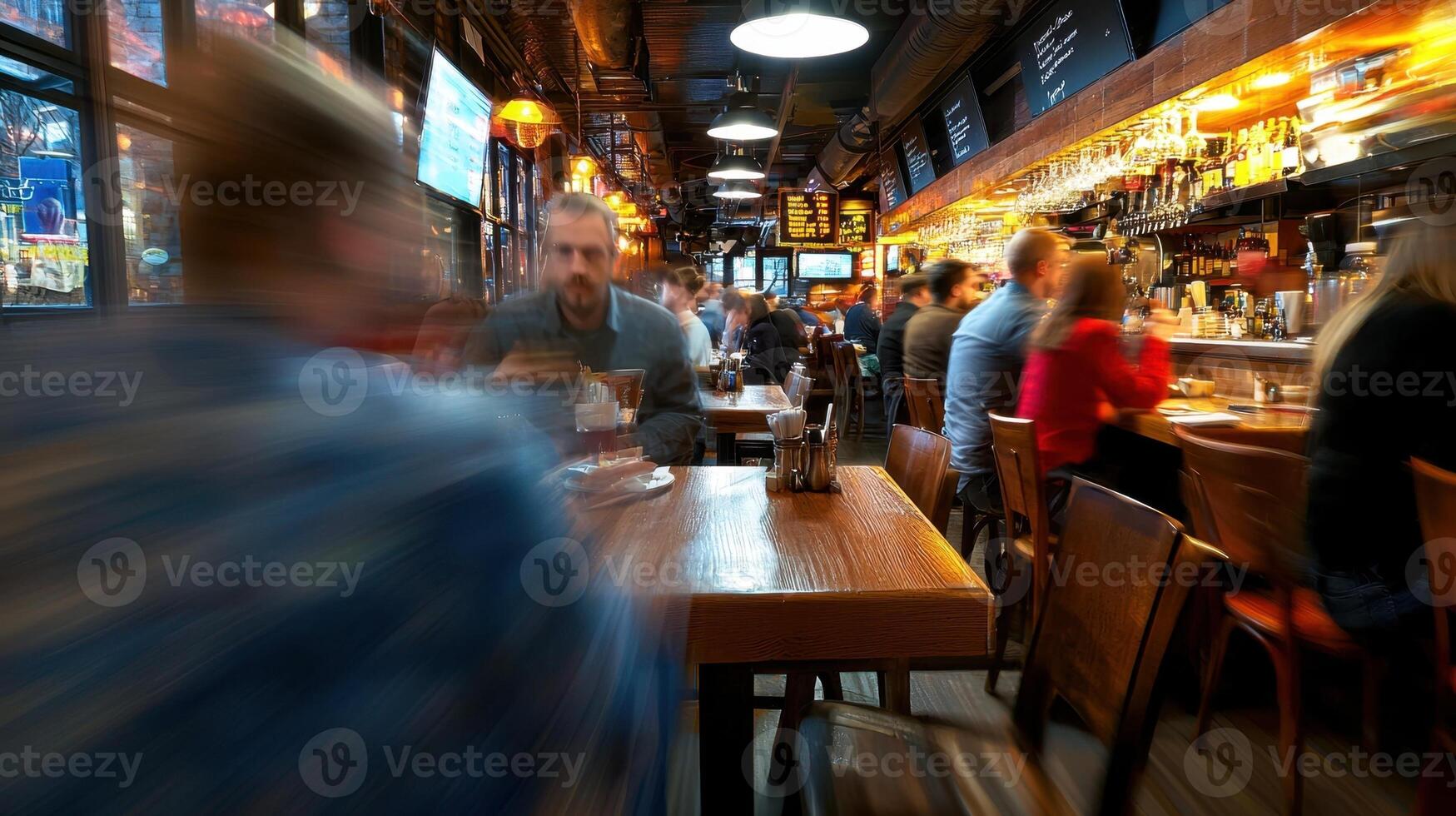 A blurry image of people sitting at tables in a bar photo