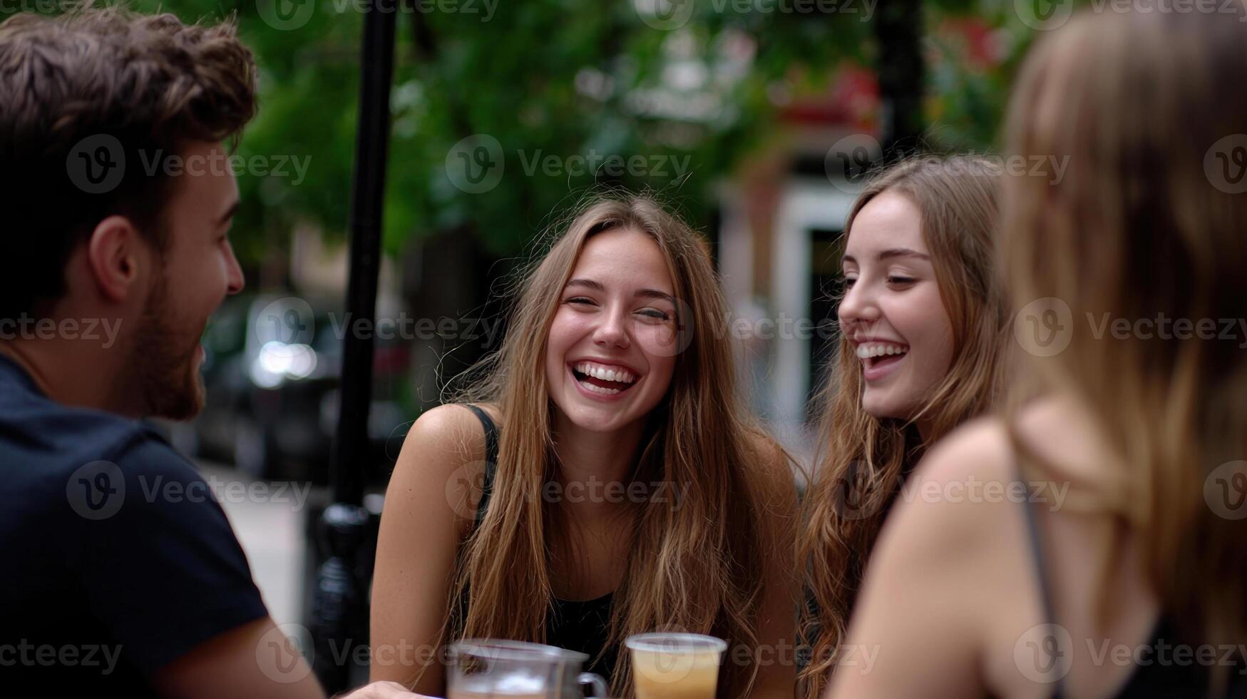 Three young people laughing at a table outside photo