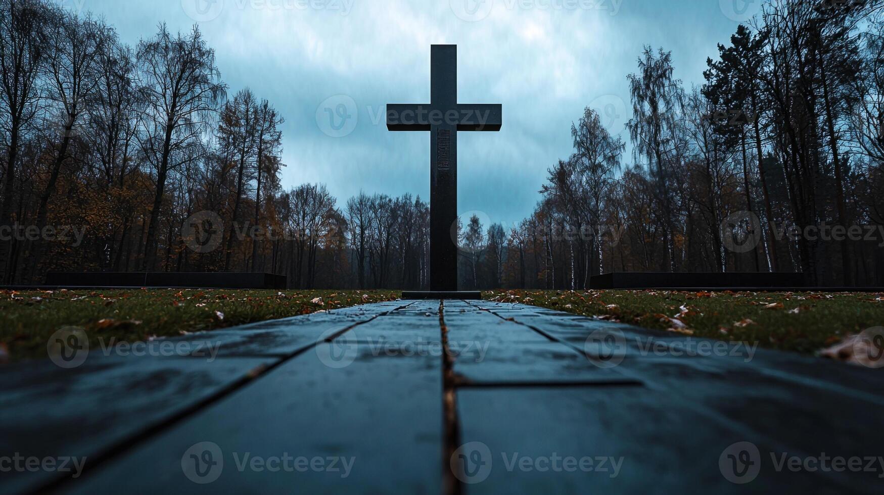 A black cross is in the middle of a path in a forest photo