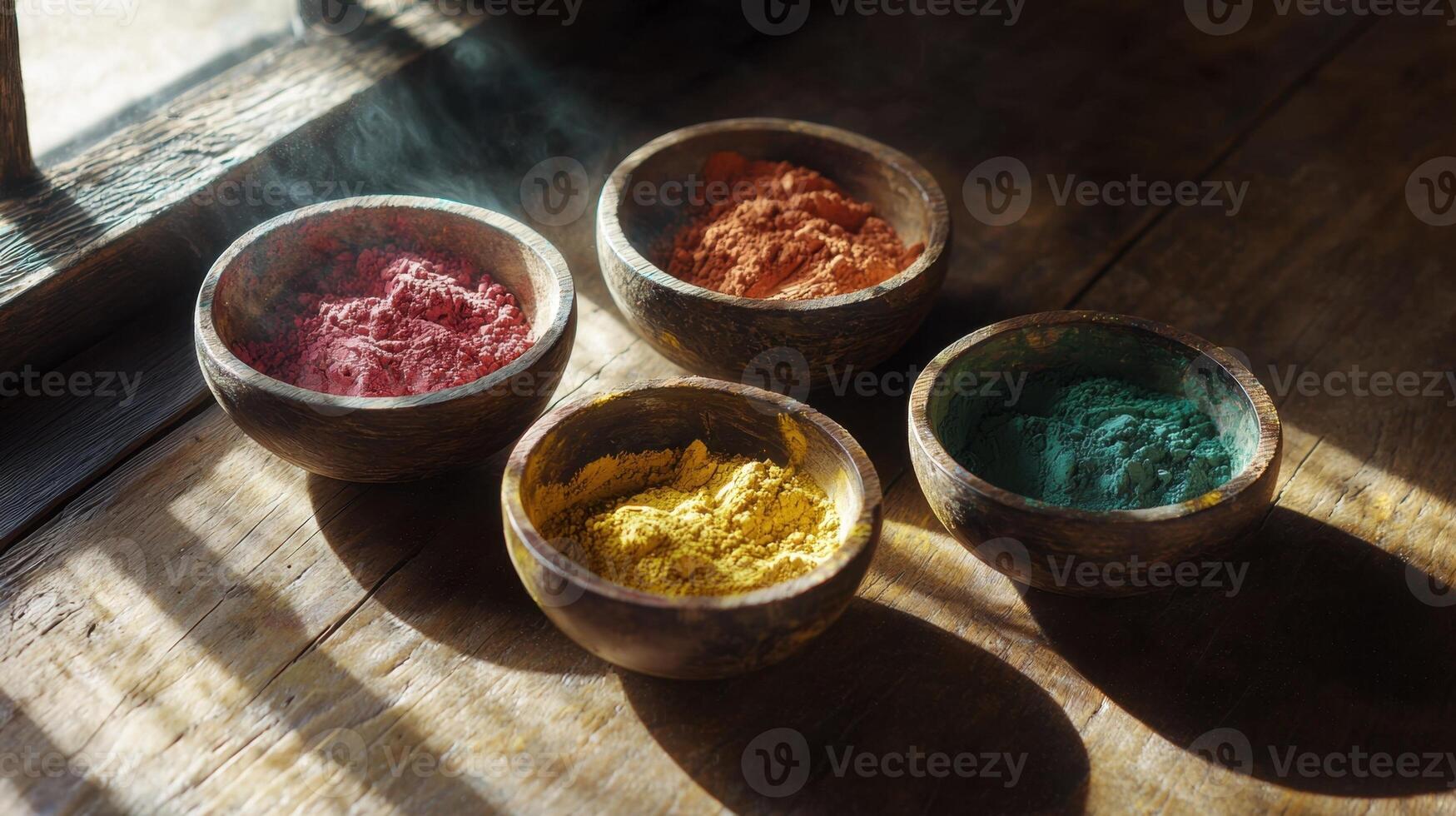 Four bowls of colored powder sit on a wooden table photo