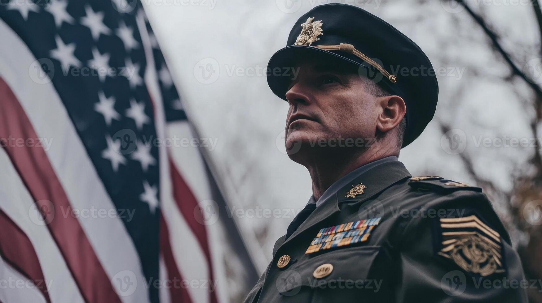 A man in uniform stands in front of an american flag photo
