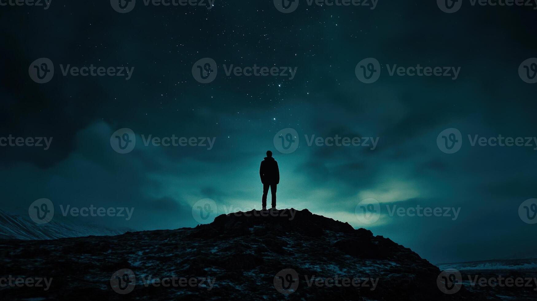 Man standing on top of mountain at night with stars in sky photo