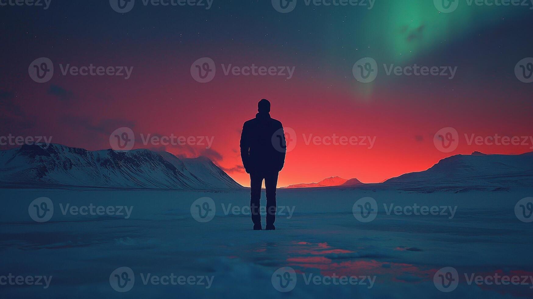 A man standing in the snow with the aurora lights in the background photo