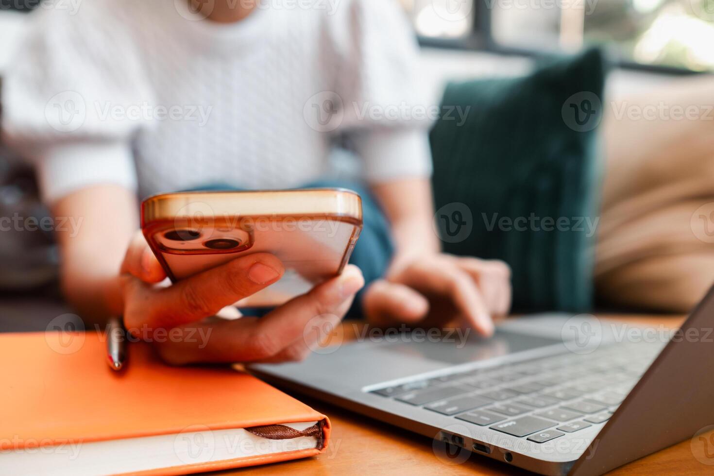 Person multitasking with smartphone and laptop, highlighting modern technology and remote work or study. photo