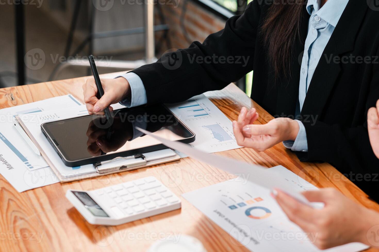 Business team working on financial analysis using a tablet and documents at a wooden desk in a modern office. photo