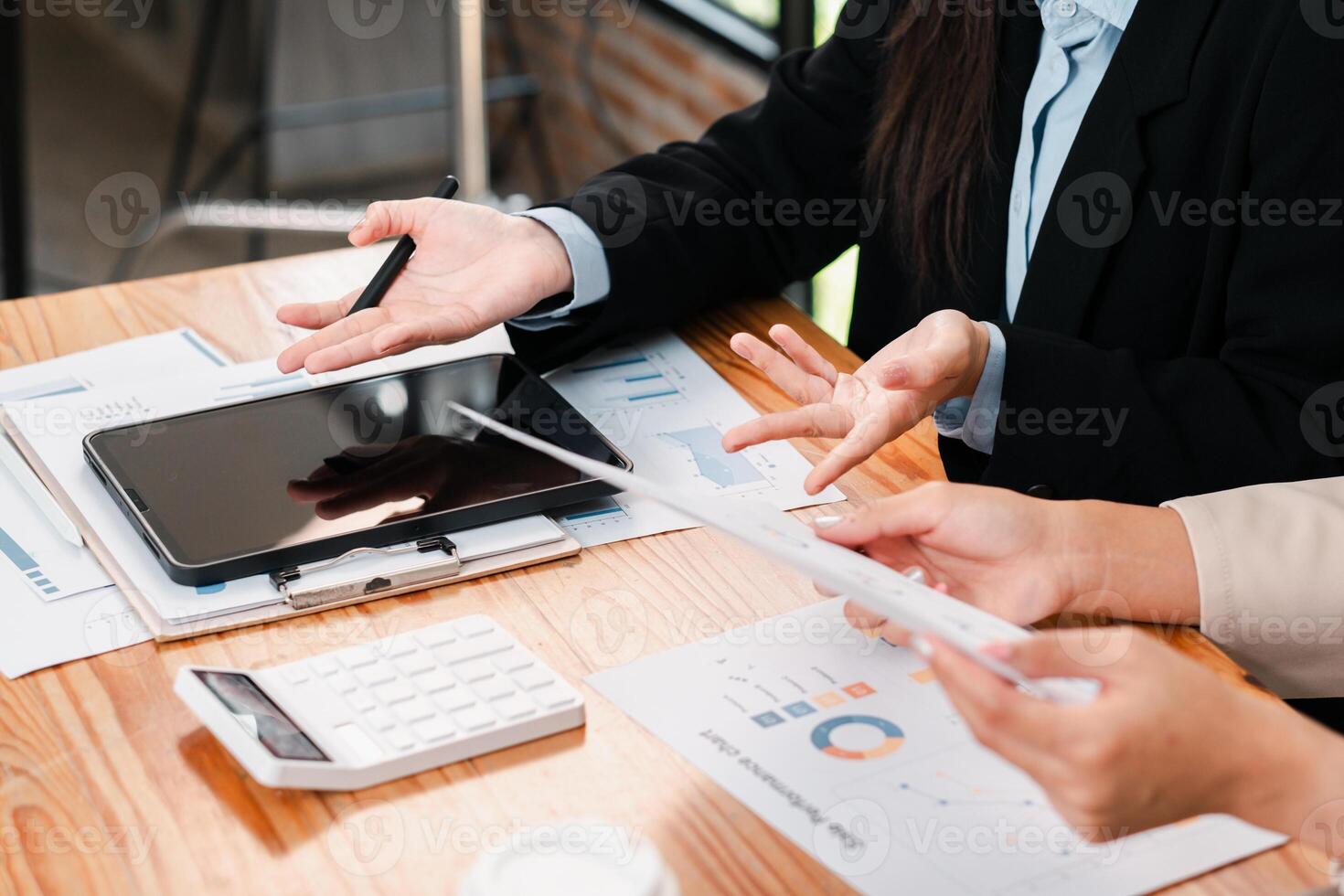 Professionals discussing financial charts and data using a tablet in a modern office environment. photo