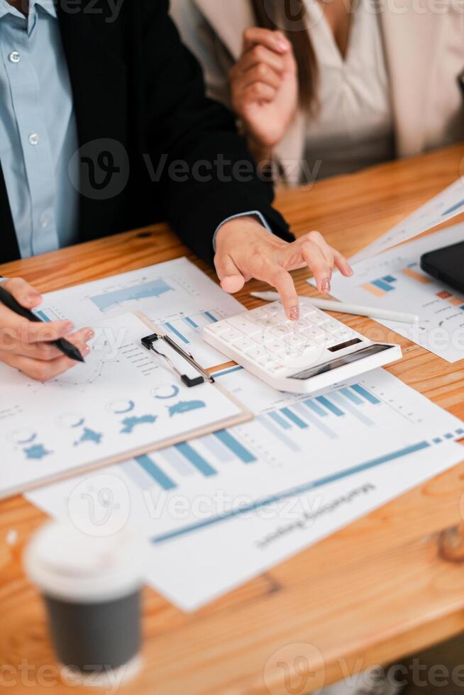 Business team reviewing financial charts and using a calculator during a meeting for strategic planning. photo