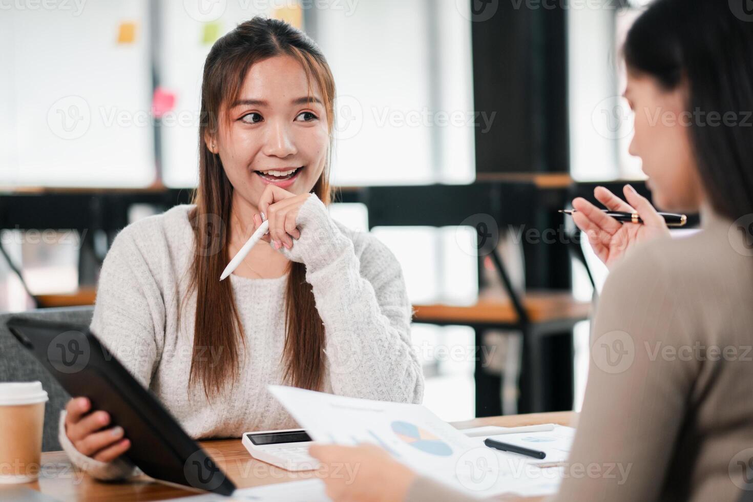 Two young professionals collaborating in a modern office, discussing ideas with digital devices and documents. photo