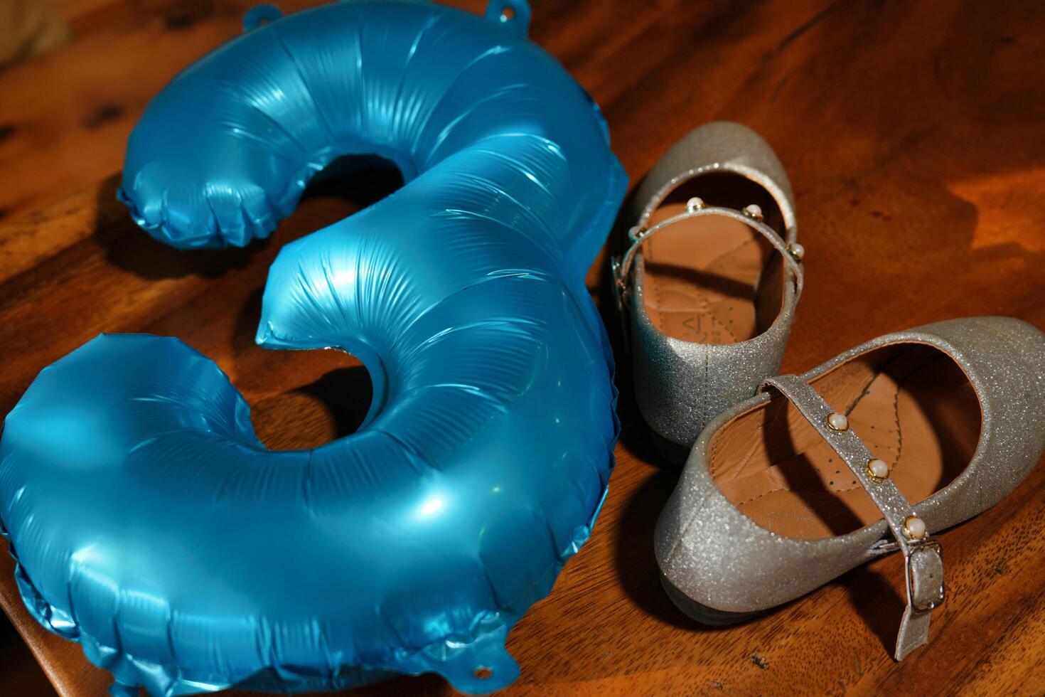 a blue balloon and a pair of shoes next to a number three photo