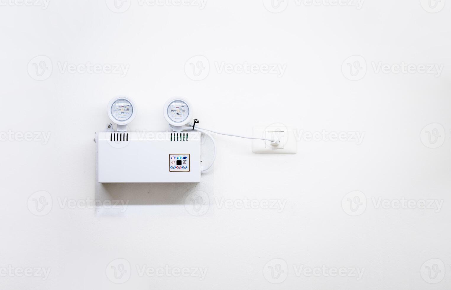 Automatic EMERGENCY LIGHT in hospital is charging and power pluging on the wall that ready to use when the power w ent out. photo