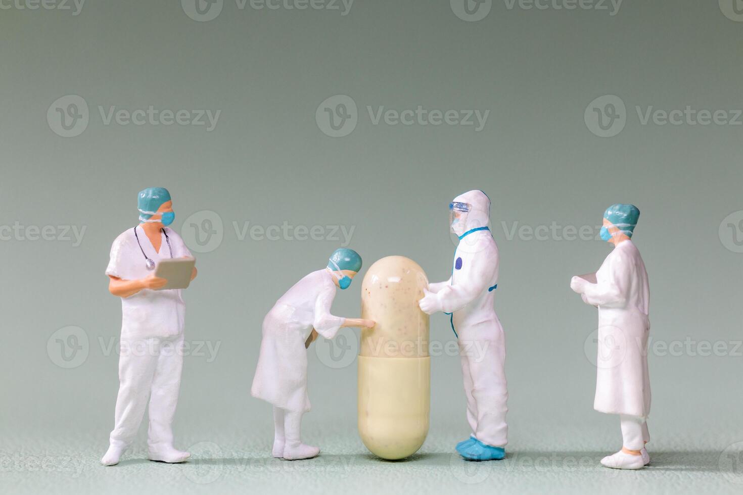 Tiny figurines of doctors and scientists examining an oversized medical capsule photo
