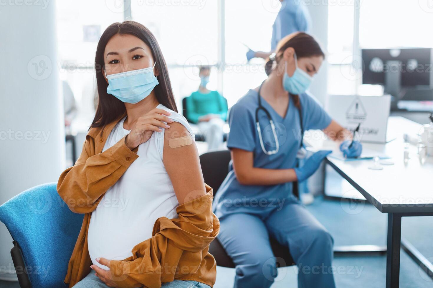flu Vaccination Concept. Portrait Of Asian Lady In Surgical Mask Showing Vaccinated Arm With Adhesive Bandage Plaster On Shoulder After Getting Corona Virus Vaccine. Antiviral Injection photo