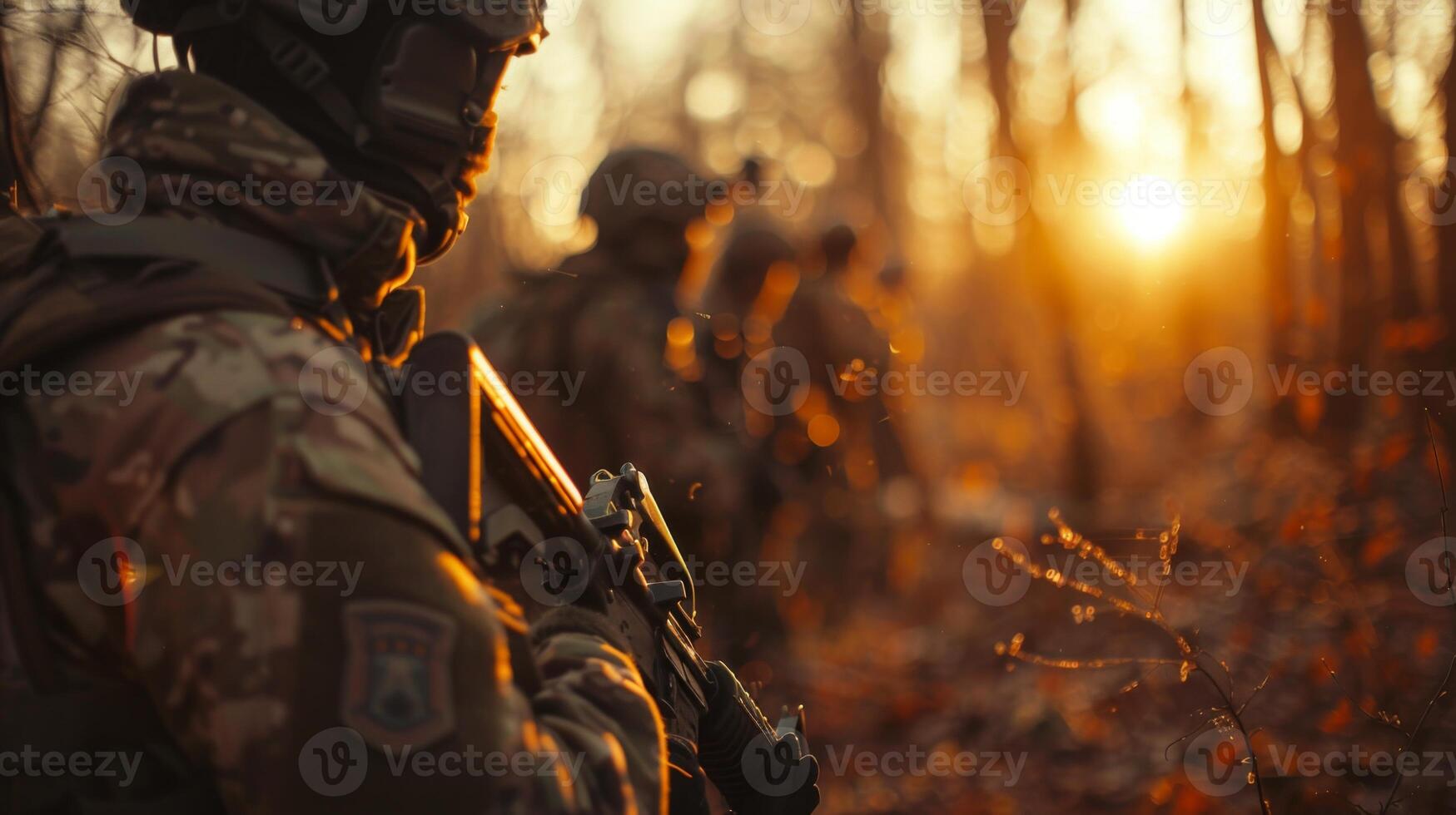 Military personnel equipped with weapons are positioned in a forest as the sun sets, highlighting their focus and readiness amidst nature's beauty. photo