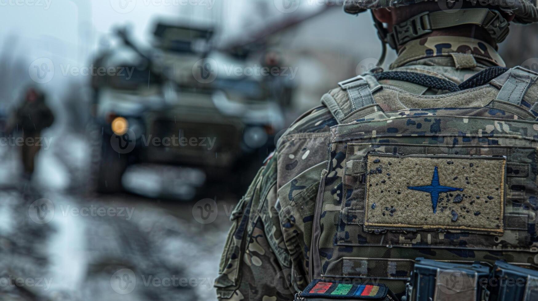 Military personnel in camouflage uniforms walk through challenging muddy terrain while armored vehicles provide support during an operation in a conflict area near sunset. photo