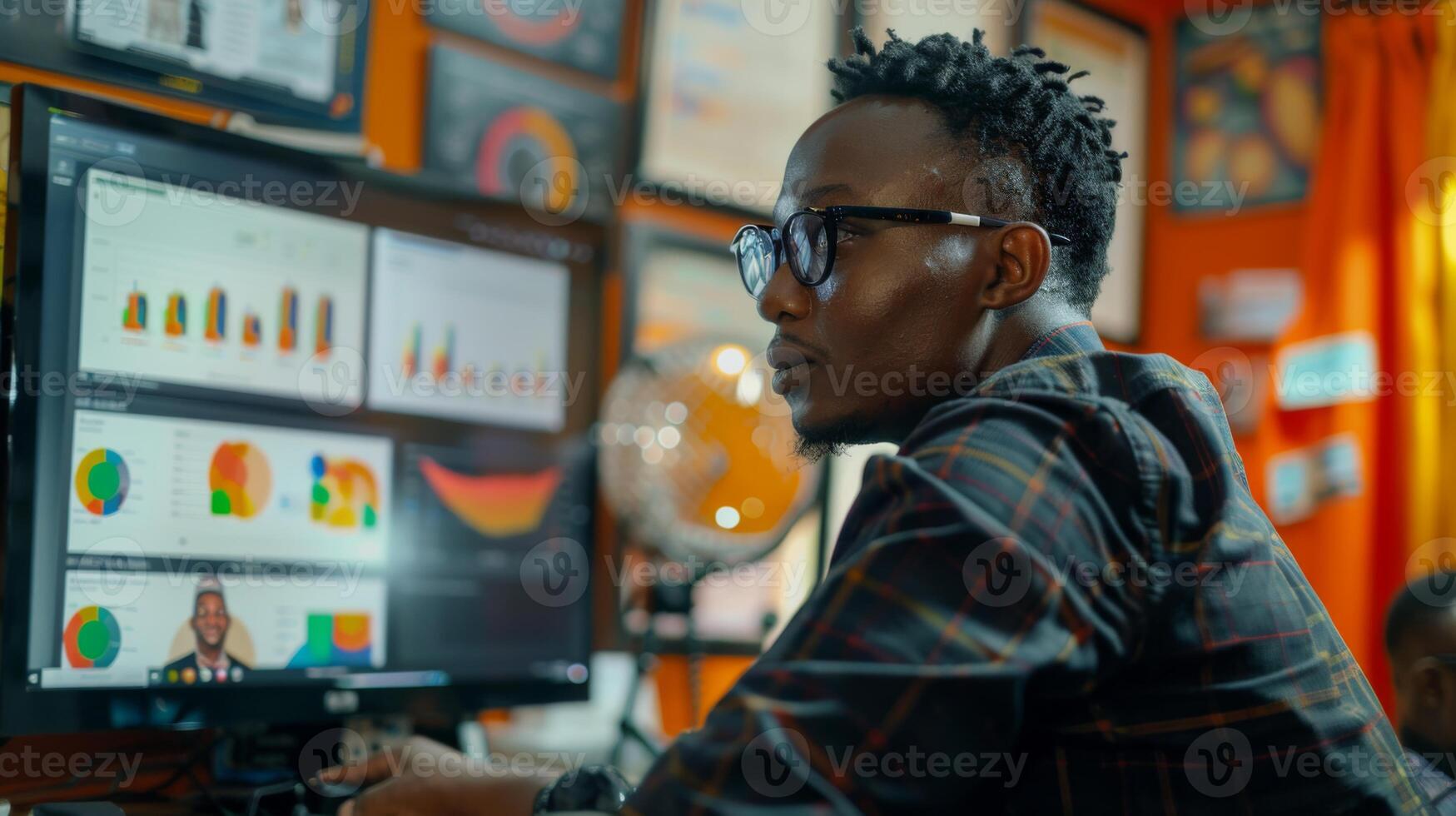 A focused individual studies various data visualizations on a large screen while seated in a lively office decorated with awards and certifications. photo