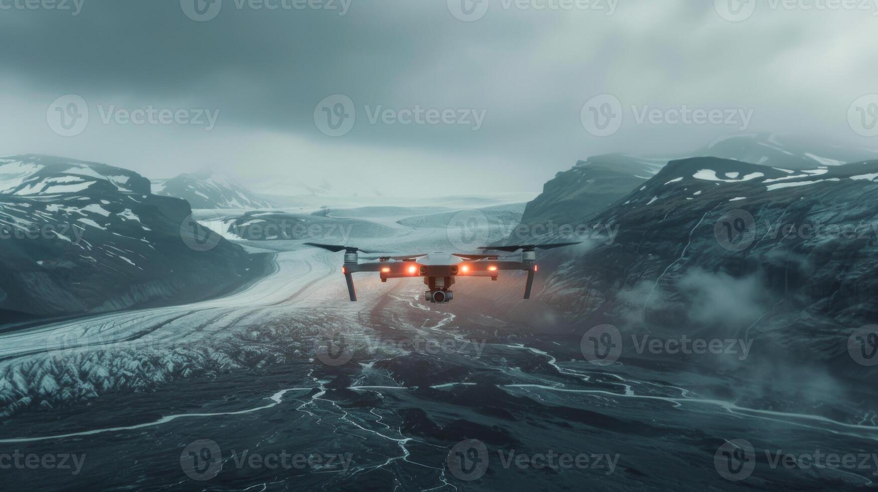 A drone hovers above a breathtaking glacial area featuring rugged mountains, sweeping ice fields, and swirling clouds, highlighting the natural beauty of the region during early morning hours. photo