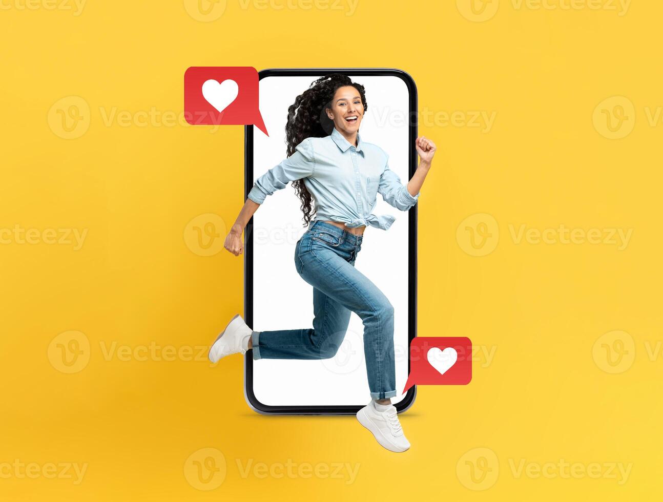 A lively woman is joyfully leaping out of a smartphone, surrounded by red heart icons, symbolizing connection and affection. The bright yellow background enhances the cheerful vibe. photo