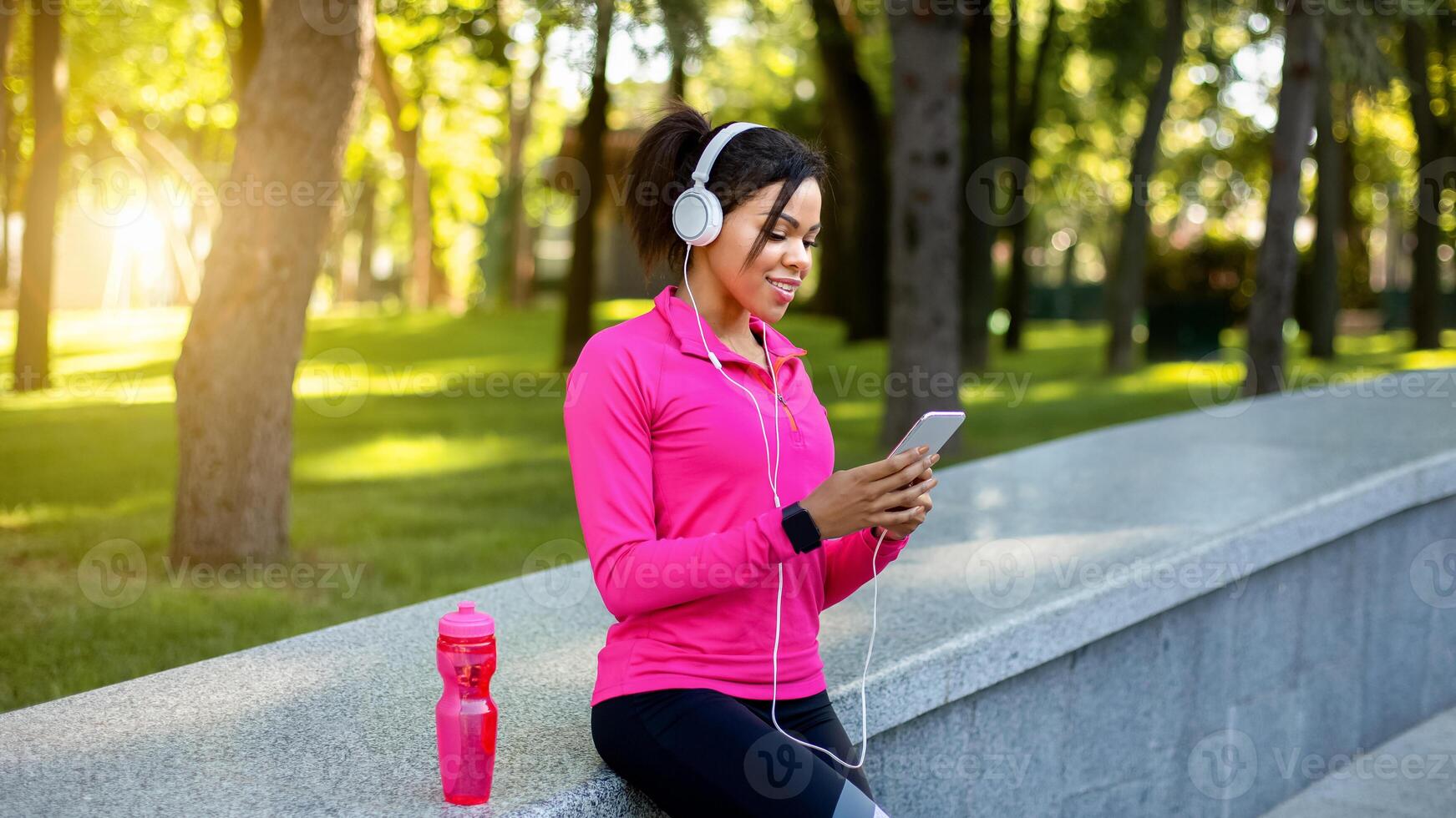 Black girl jogger using sport app for smartphone while resting during training in public park, empty space photo