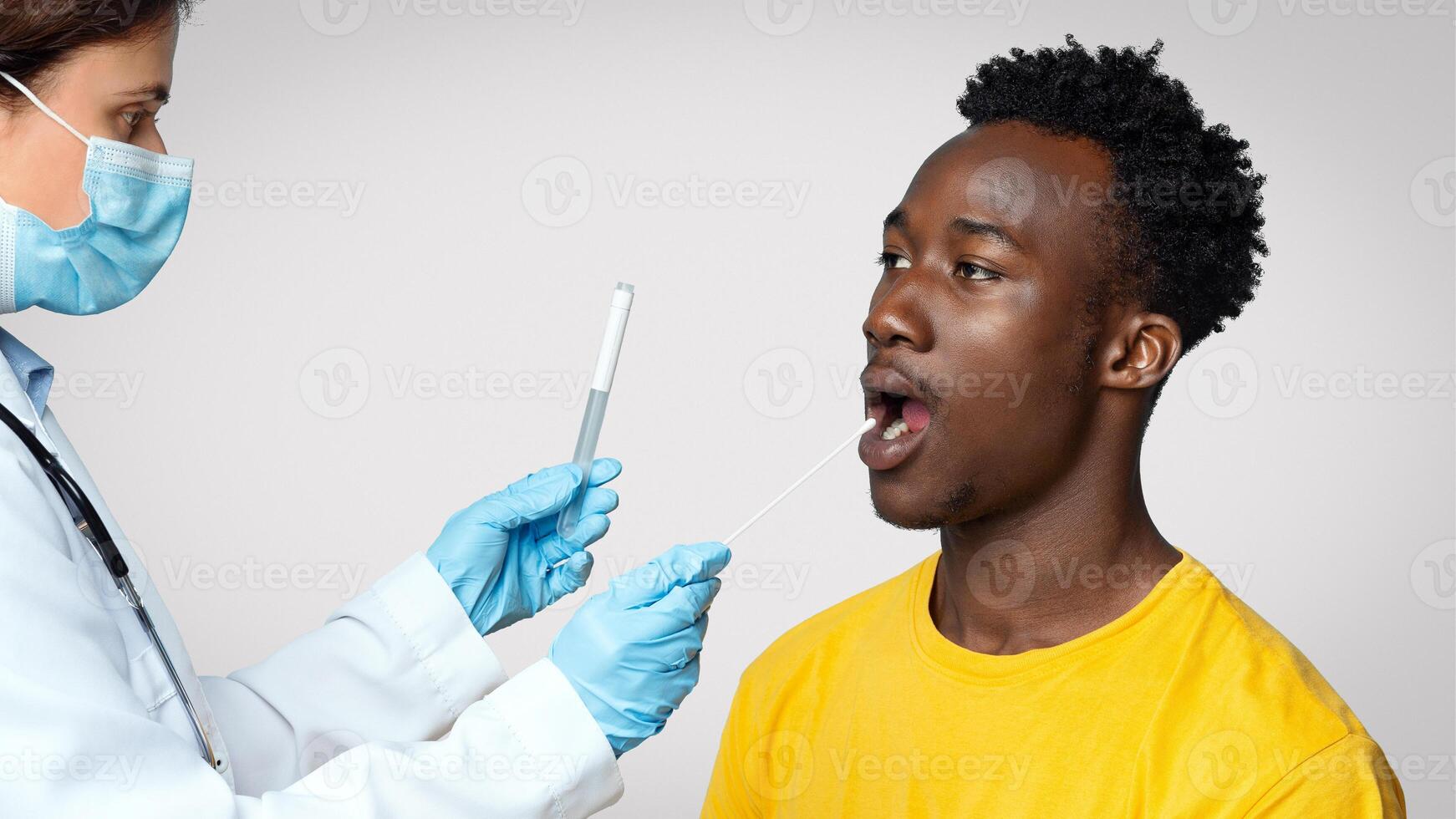 PCR Coronavirus Test. Doctor Taking Swab From Black Male Patient's Mouth, Young African American Man Undergoing Covid Diagnostic Procedure, Sitting Over Blue Studio Background, Free Space photo