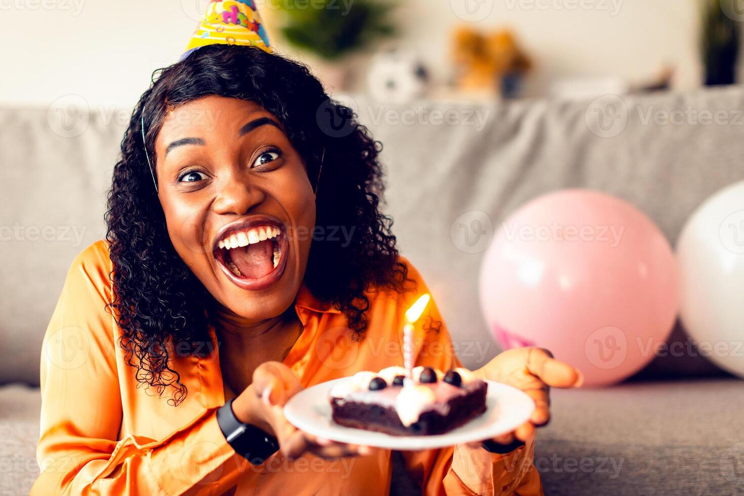 Happy Birthday. Excited African American Female In Festive Hat Holding B-Day Cake With Candle Congratulating You Smiling To Camera Indoors. Joy Of Holiday Celebration Concept photo