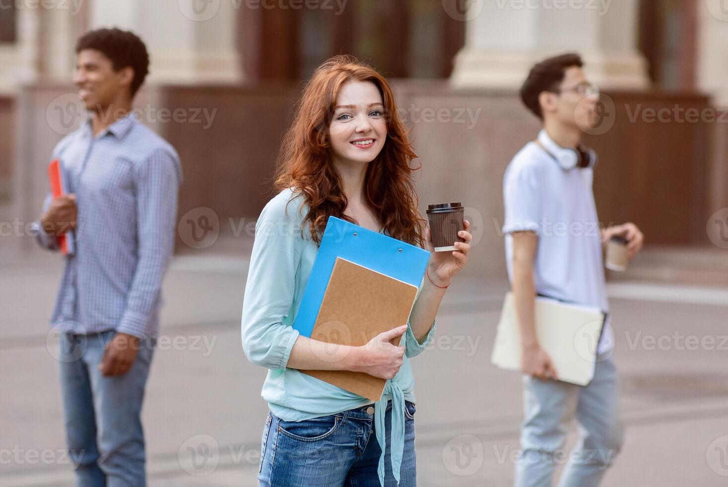 Cheerful Student Girl Having Coffee During Break Standing Outside University Building, Smiling To Camera photo