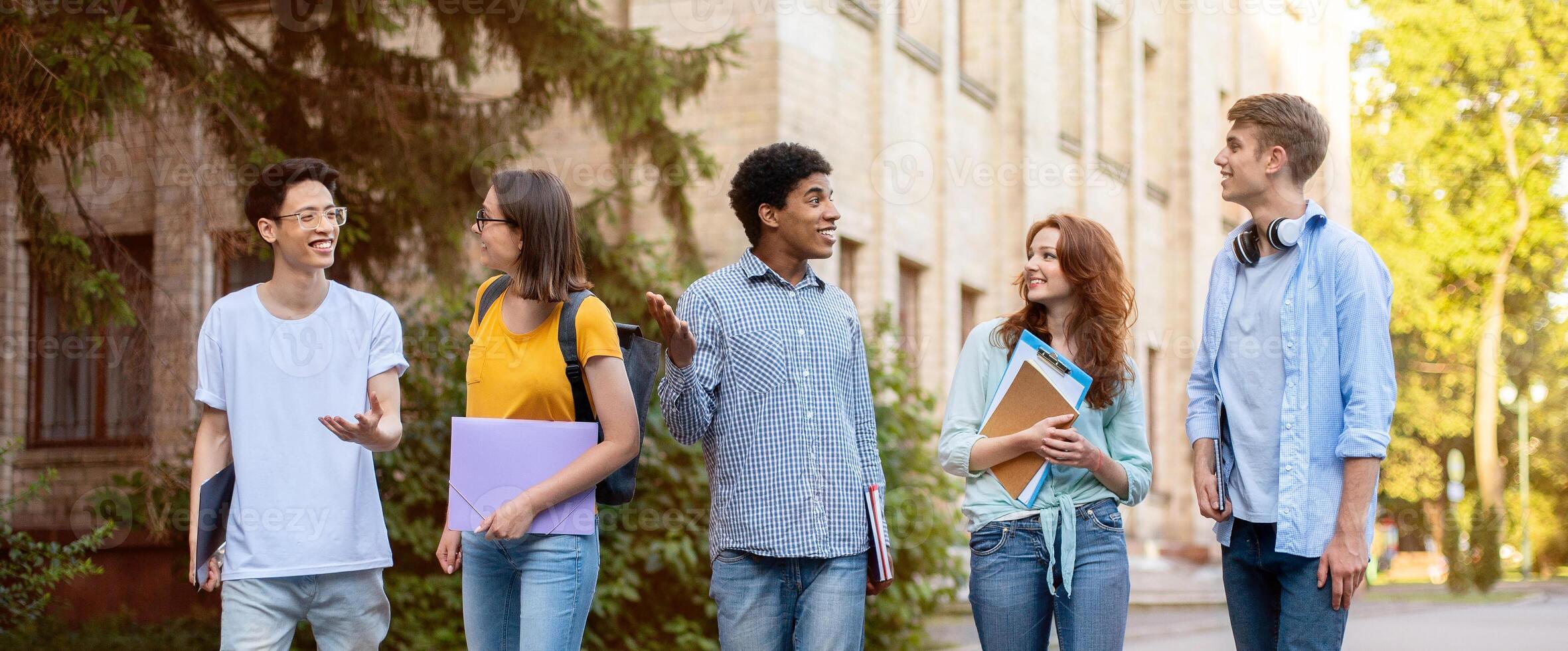 Group Of Multicultural First-Year Students Walking Near University Building Outside. Higher Education Concept. photo