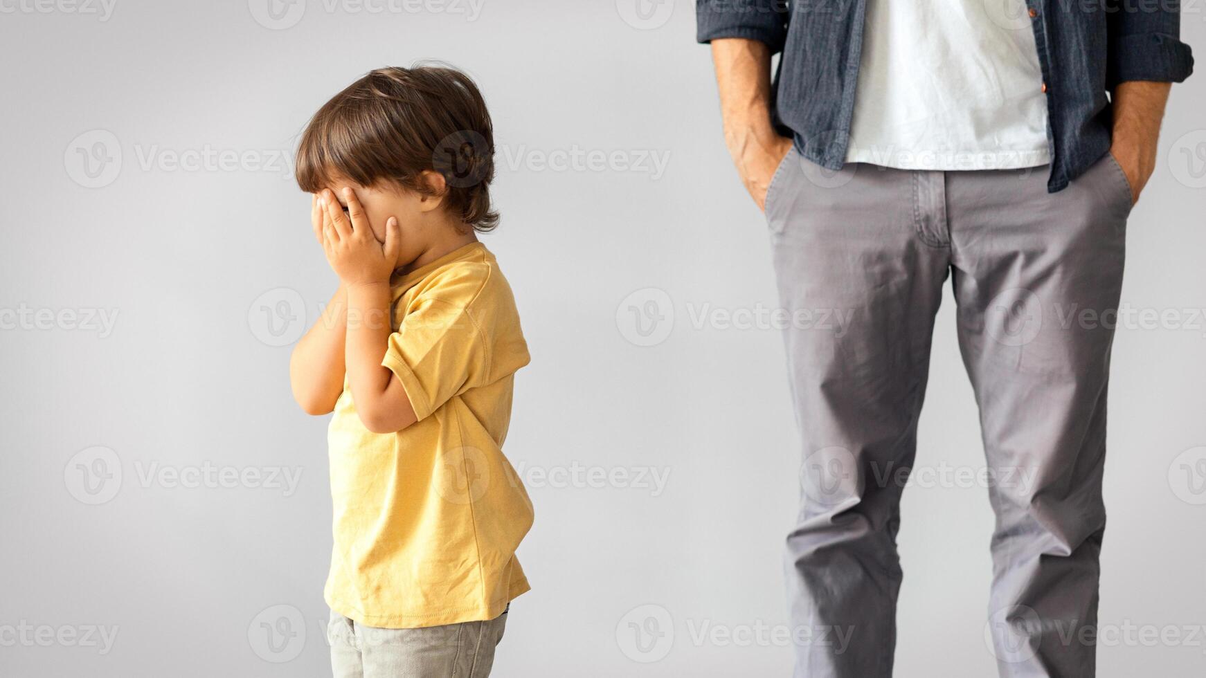 Kids psychological traumas. Little baby boy crying alone, feeling lonely and abandoned, unrecognizable indifferent father standing behind with hands in pockets, ignoring child photo