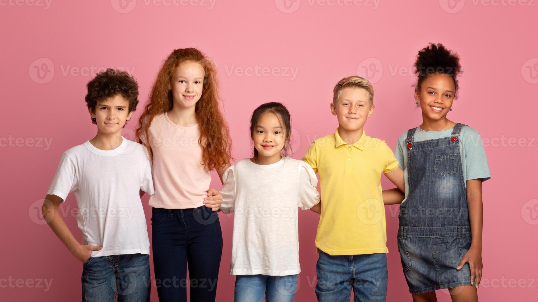 Back to school concept. Happy diverse boys and girls posing on pink background photo