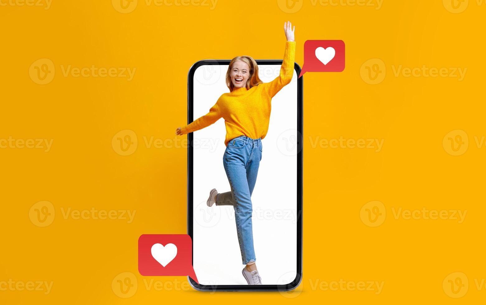 A person wearing a bright yellow sweater playfully poses while holding a smartphone that displays love icons. photo