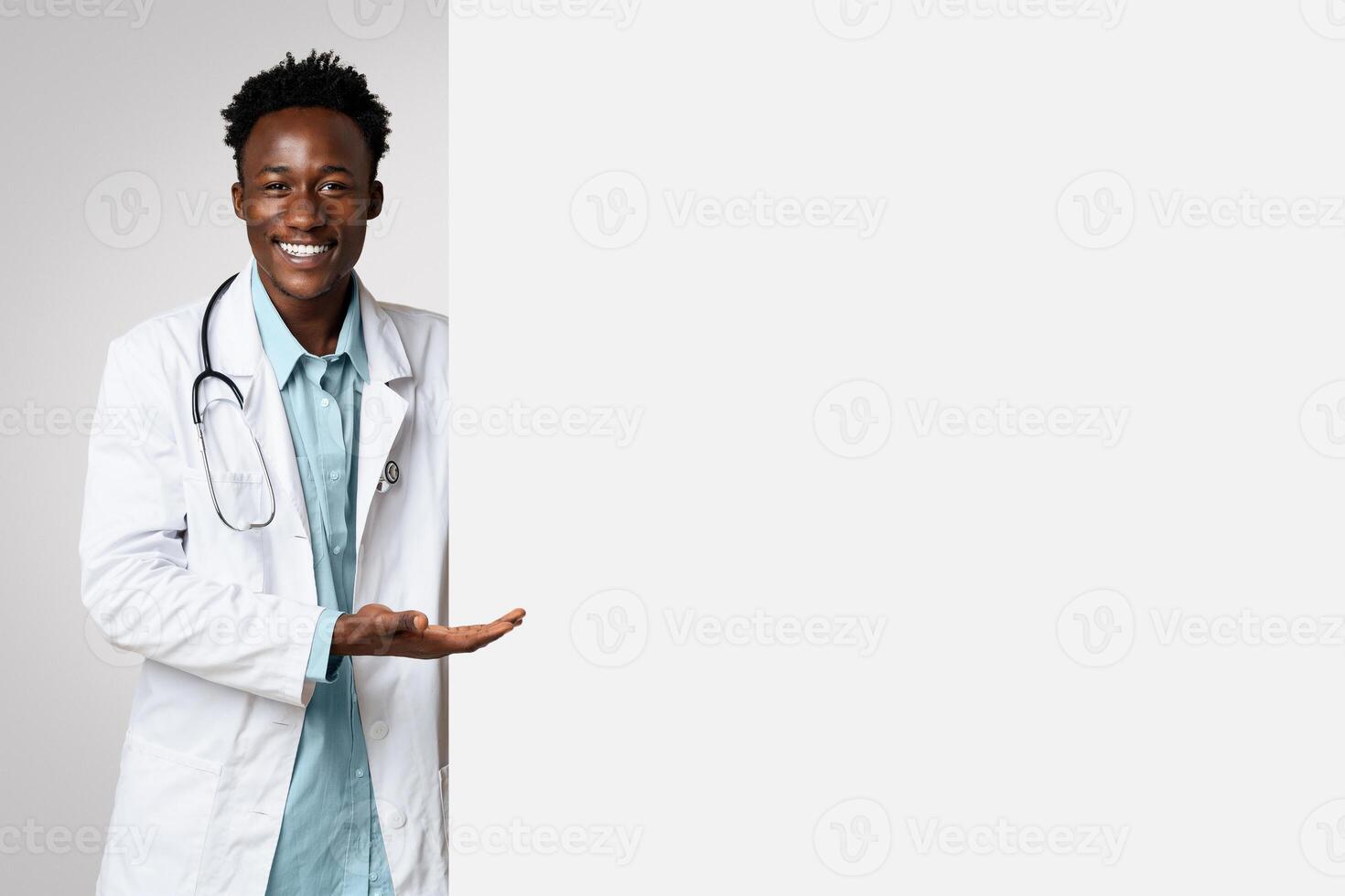 Smiling black male doctor pointing at big blank advertisement board with open palm, professional therapist demonstrating empty copy space for text or vaccination campaign design, panorama photo