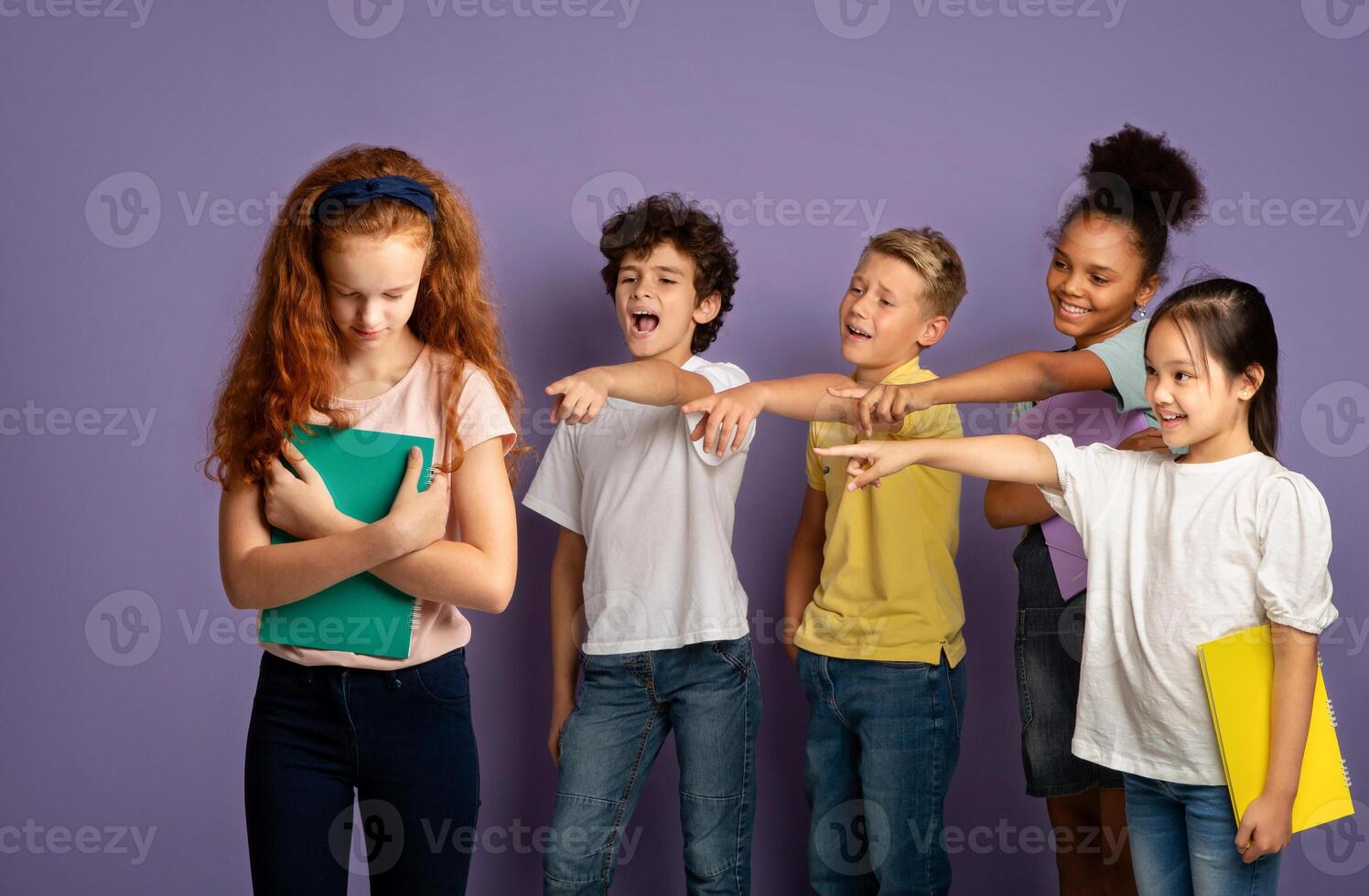 Group of mean schoolchildren bullying their upset red-haired classmate on violet background photo