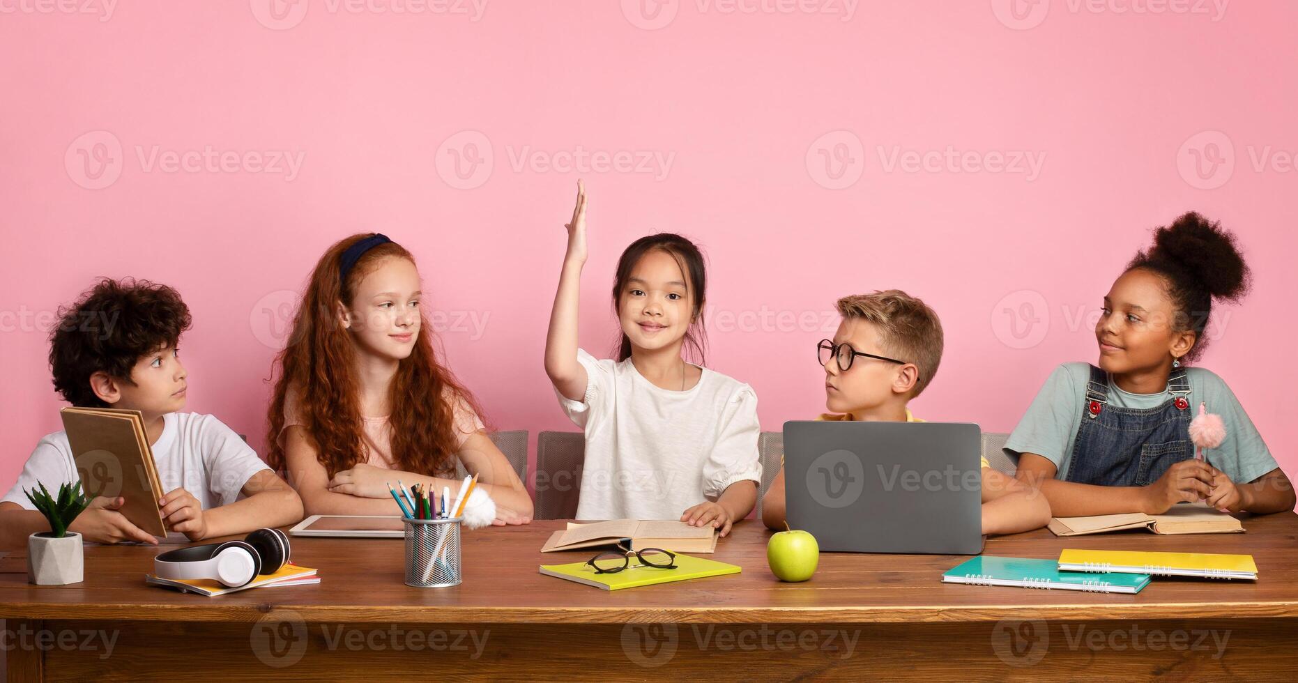 Industrious Asian girl with her classmates studying at desk over pink background, empty space. Panorama photo
