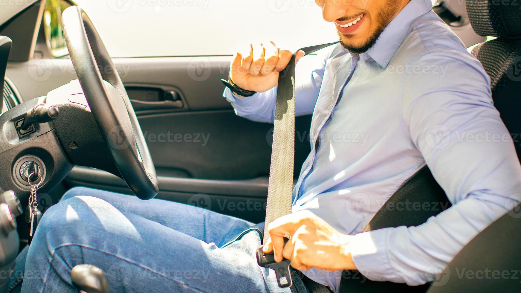 Positive arab guy in formal outfit fastening automobile seatbelt, handsome middle-eastern man entrepreneur driving nice car, going to office, sde view, copy space. Safety driving concept photo