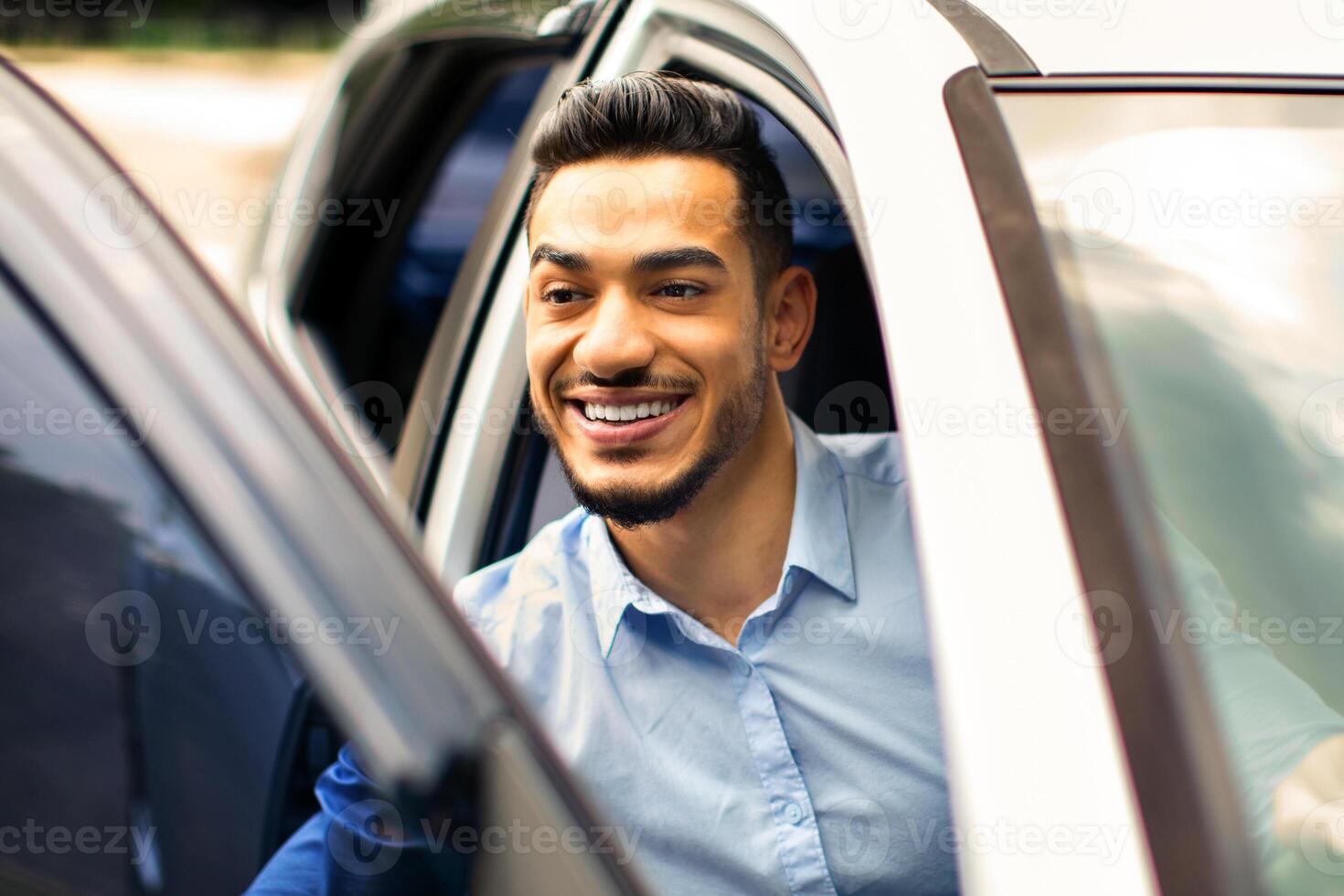 Closeup of middle-eastern young businessman getting out auto, copy space. Handsome arab man entrepreneur going to business trip, getting into brand new automobile, driving his nice car photo