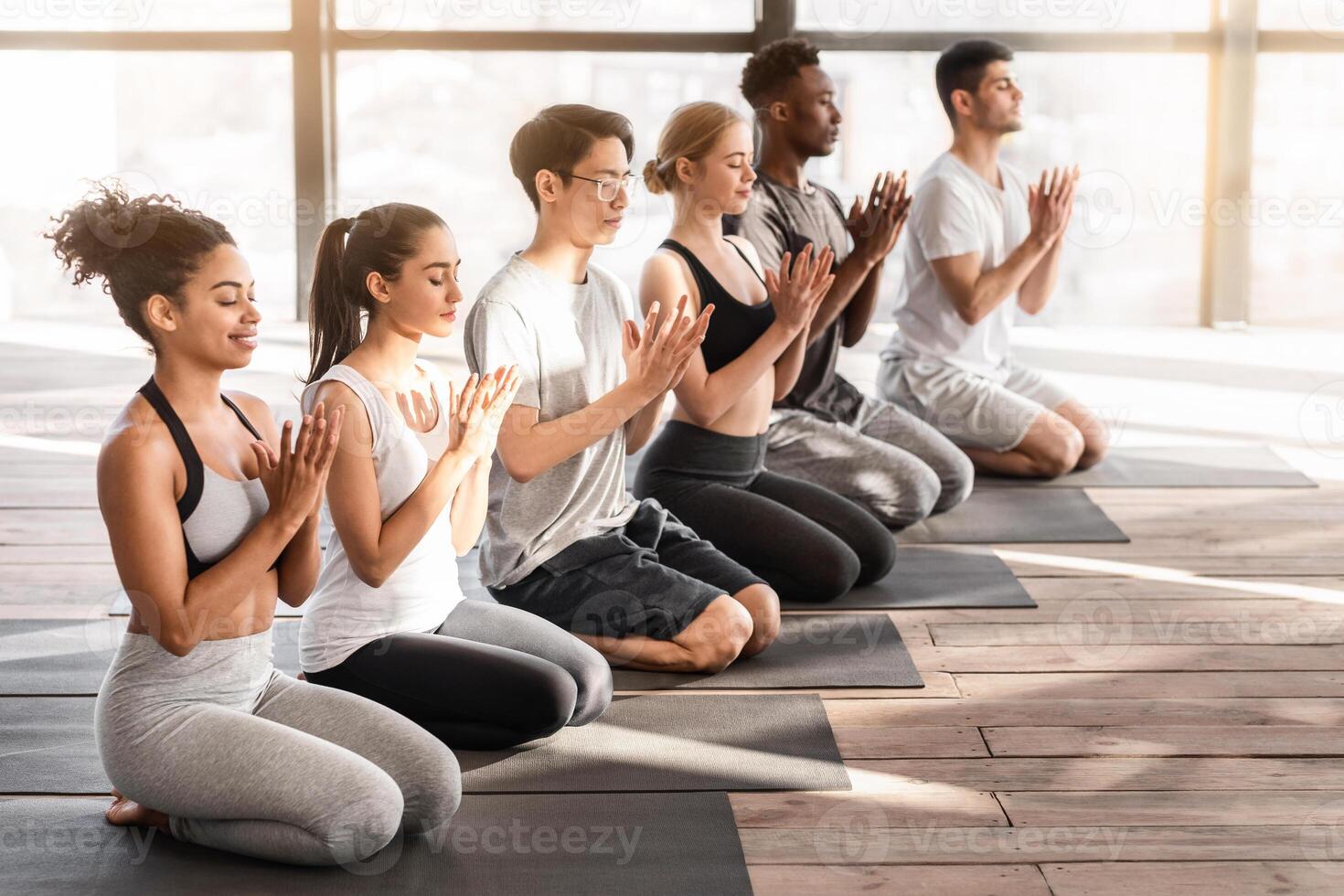 Yoga Lesson. Group of sporty young people doing lotus seal gesture, and meditating in studio together, side view with free space photo