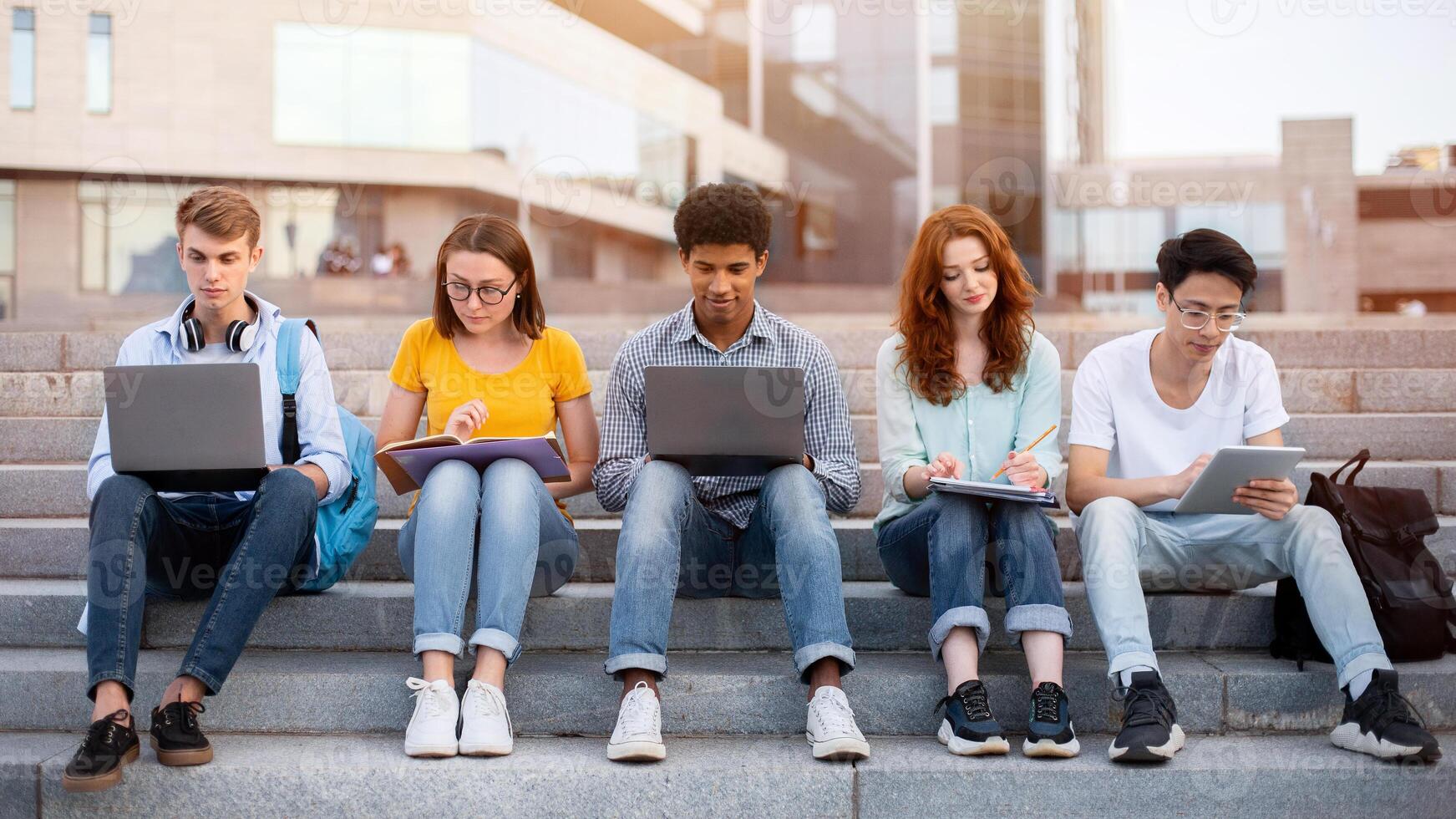 Multiracial Students Learning Preparing For End-Of-Semester Exams Together Sitting On Steps Outside University. College Lifestyle photo